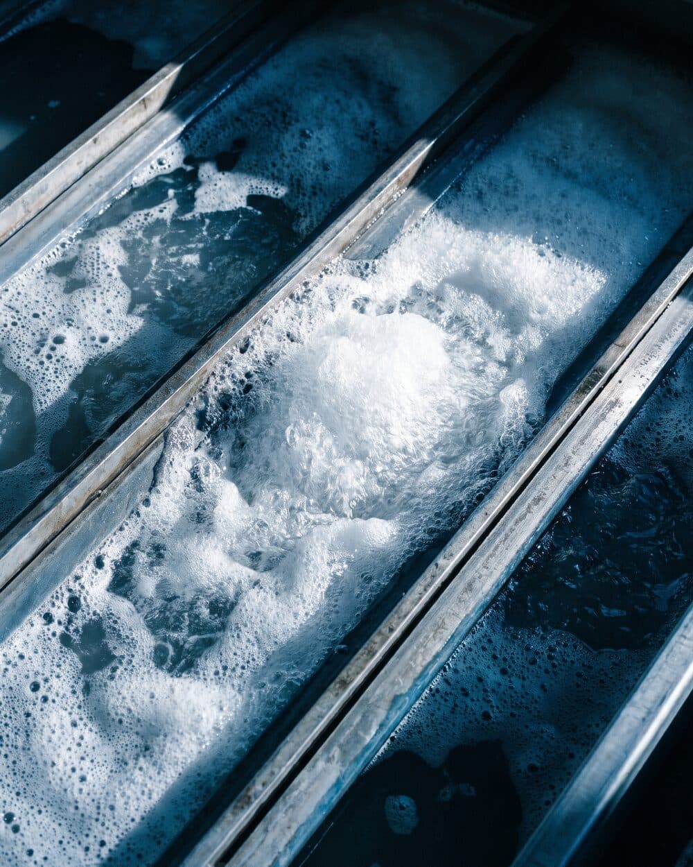 Nahaufnahme: Gitterrost eines Wasserstrahl-Schneidtischs mit Wasser und Schaum