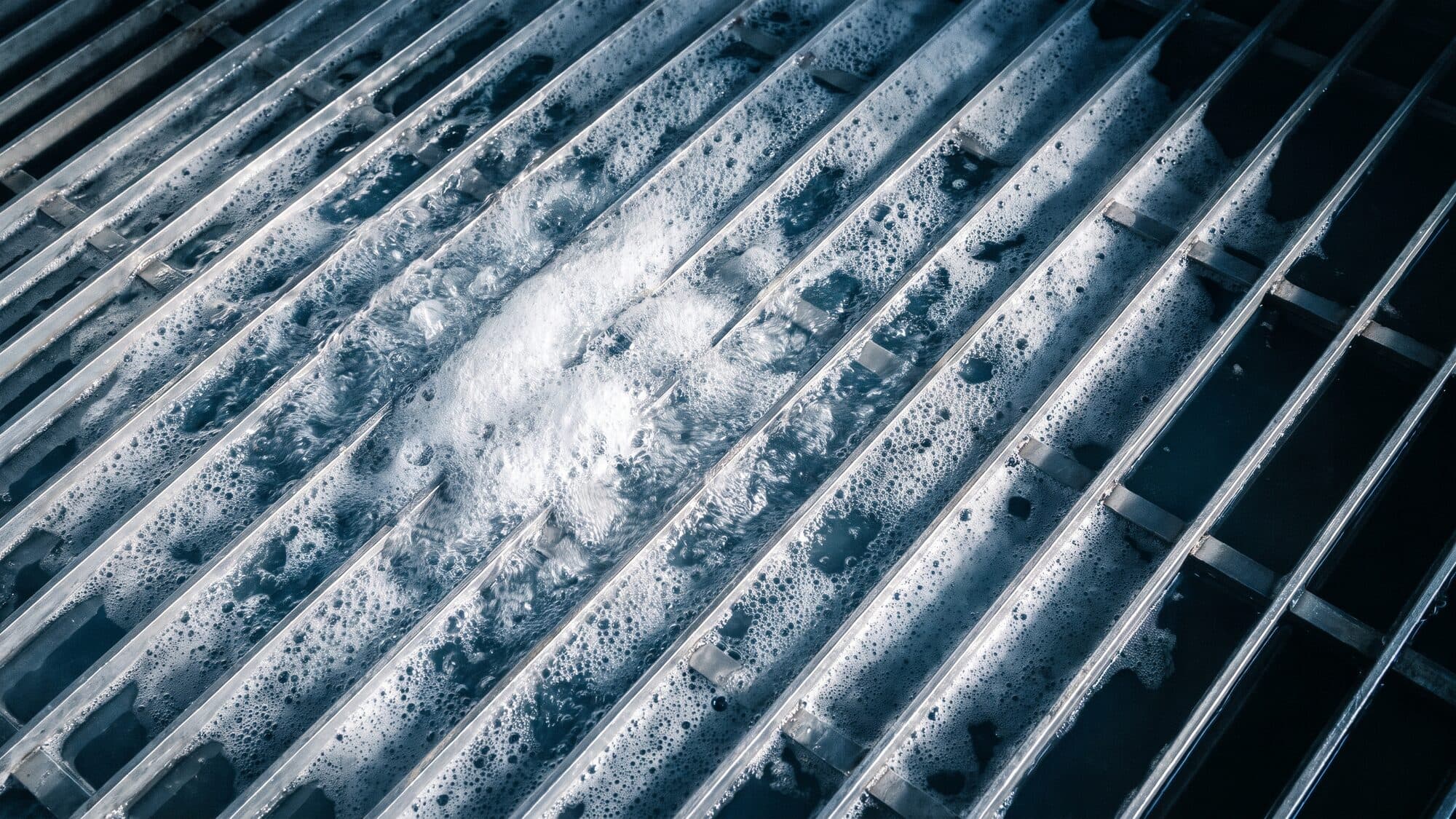 Nahaufnahme: Gitterrost eines Wasserstrahl-Schneidtischs mit Wasser und Schaum